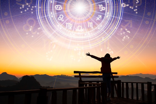 Woman raising hands looking at the sky. Astrological wheel projection,